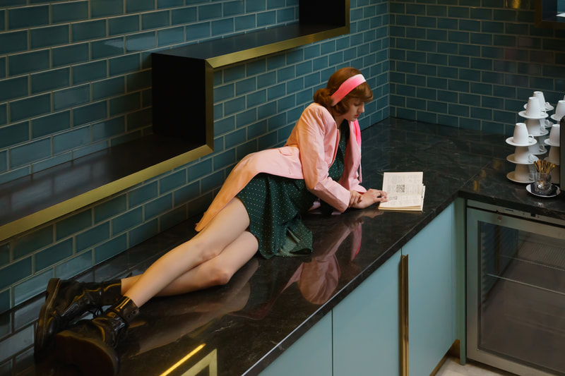 Model, Young girl in pink coat lying on a kitchen counter
